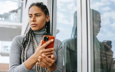 A woman holding a smartphone, looking disappointed at a message.