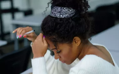 An African American woman in a white blouse taking a written test.