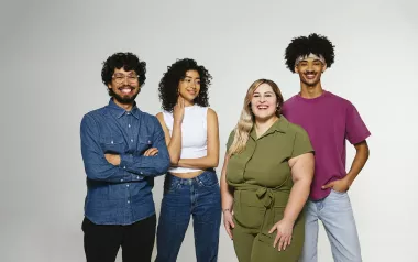Four individuals of various ethnicities smile for a photo. 