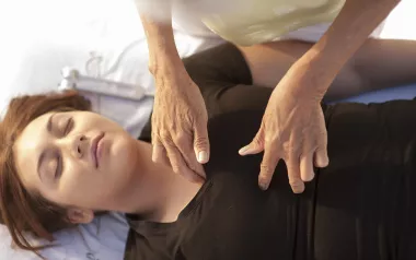 Woman lying on massage table receiving therapeutic touch.