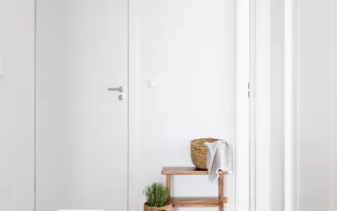 A hallway in an office leading to a small table with a towel and a door.