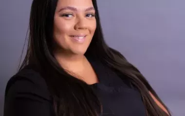 carol reyes ryan with long dark hair in a black shirt smiling. 