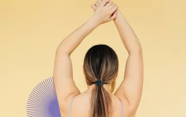A woman stretches her shoulder, reaching both arms above her head.