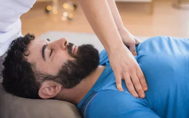 A massage therapist works on a client's pectorals. 