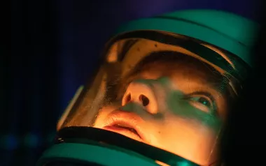 A person in a deep-sea diving suit stares into the depths.