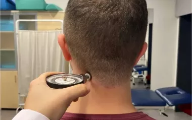 A client has a pain pressure threshold algometer held at their neck.