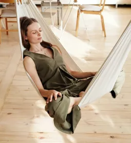 A woman sits in a hammock indoors.