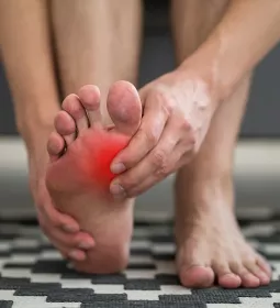 A person massages their own foot, which appears to be in pain via red coloring near their big toe.
