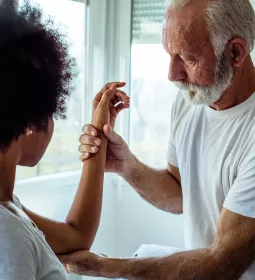 A client has their left arm examined between the wrist and the area of the upper elbow.