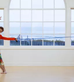 Judith Aston in a red top stretches in a dancing motion.