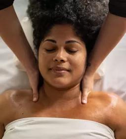 Massage therapist applying massage strokes to female client on massage table.