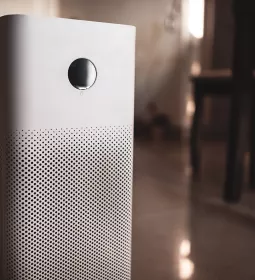 a white air purifier unit plugged into a wall.