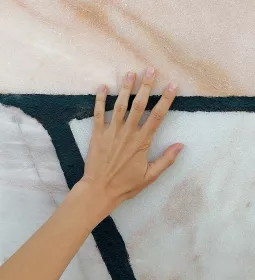 a hand with the palm splayed up against a painted abstract wall.