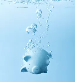 a light blue piggy bank sinks in water.