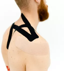 Kinesiology tape applied to a person's back and shoulder.