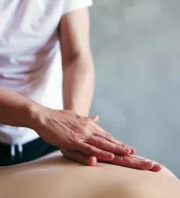 A practitioner lays hands on a client.