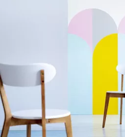 two white chairs seated in a pastel colored room full of light.