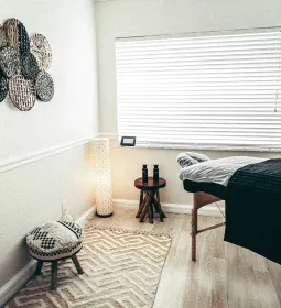 an empty massage room with a wooden table and decor on the wall. the window is open.