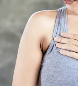 a white woman in a tank top holds a spot on her chest.