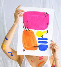 Person holding up a sheet of paper with abstract art in front of their face.