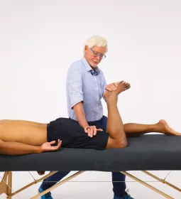 Erik Dalton, PhD, provides massage to a client's leg while the client is prone on a massage table.