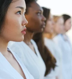 A line of women of all different skin tones, colors, and hair styles, facing to the right.