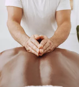 A massage therapist massages a client's back.