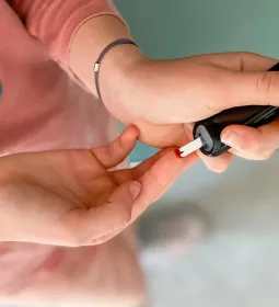 A person self-administers a blood test to their finger.