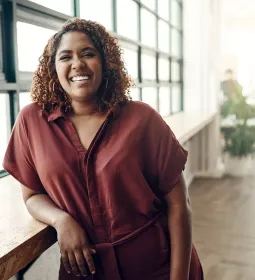A smiling woman leaning on a countertop.