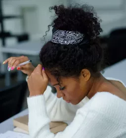 An African American woman in a white blouse taking a written test.