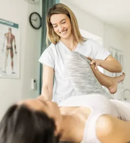 A female massage therapist stretches the leg of a client.