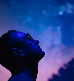 A man gaves up into the starry night sky with his head tilted backward.