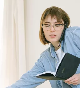 young woman talking on the phone and opening a notebook at the same time.