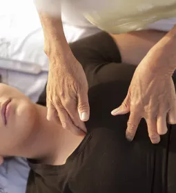 Woman lying on massage table receiving therapeutic touch.