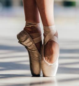 A pair of feet on tip toe in pointe shoes.