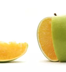 A piece of fruit that is green apple on the outside, but orange on the inside.