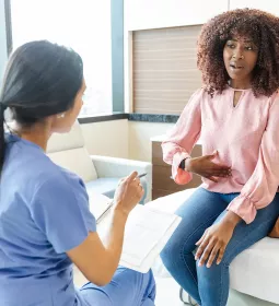 A Black female client points to her stomach in discussion with a therapist.