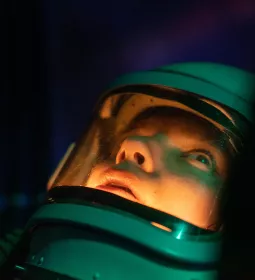 A person in a deep-sea diving suit stares into the depths.