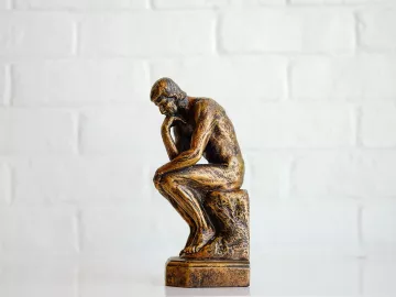 A miniature version of the statue The Thinker stands on a table