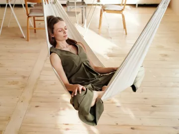 A woman sits in a hammock indoors.