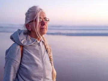 An elderly lady looks out across an ocean.