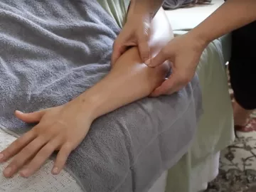 A massage therapist's hands work on a client's forearm.