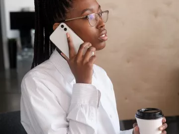 Black woman on cell phone in office setting.