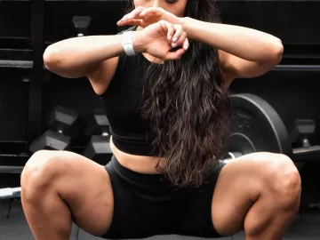 Fit female doing squat exercises at a gym. 