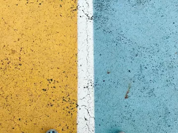 Conceptual, feet standing on divided road, half blue, half yellow.