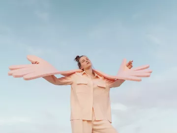 A woman holds giant foam hands that symbolize self-care and empathy.