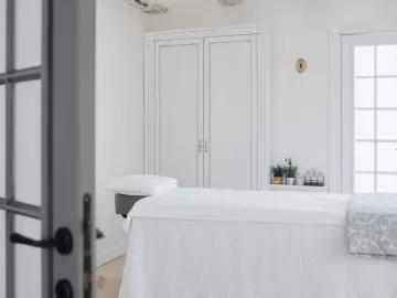 an empty massage table with white sheets and drapes.
