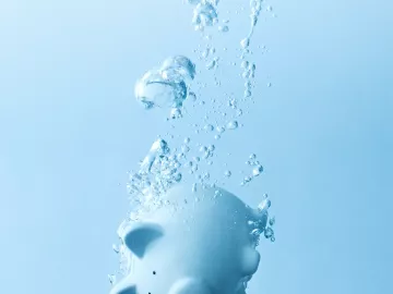 a light blue piggy bank sinks in water.
