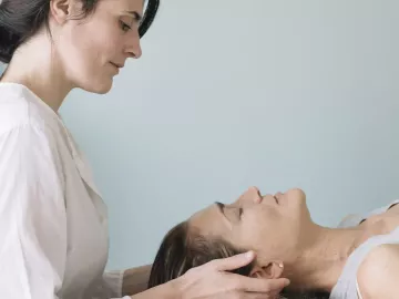 a female MT working on the head and neck area of a prone female client.