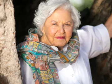 portrait of deborah szekely in her 80s. She's wearing a colorful scarf.